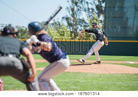 Baseball pitcher winding up to pitch to left handed batter.