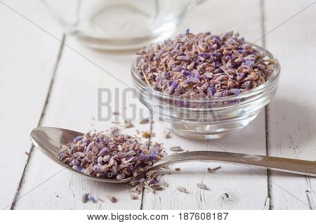 Dry lavender flowers and essential oil on white background . Aromatherapy oil in transparent bowl. Lots of dried seeds in transparent glass surrounded by dry violet flowers. Awakening the senses.