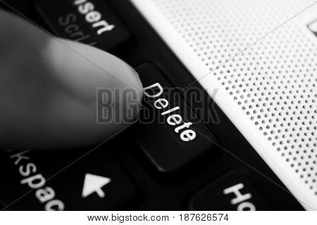 Finger hit the delete button close up.