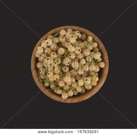 White currants in a wooden bowl. Top view. Ripe and tasty currants isolated on black background.