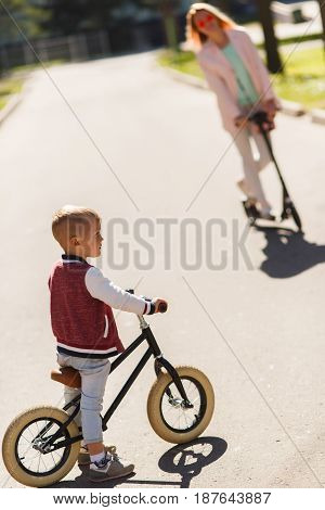 Woman with son on scooters in park during day