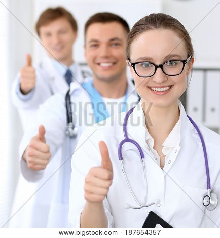 Happy doctor woman with medical staff at the hospital. Thumbs up.