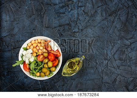 Spring vegetable salad with arugula cherry tomatoes chickpeas olives and feta cheese. Buddha bowl. Top view. Place for text.