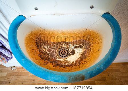 Old dirty white and blue sink with brown stain