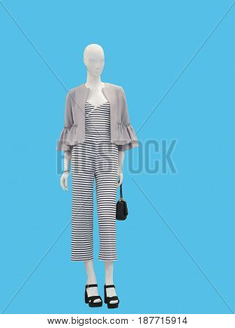 Full-length female mannequin dressed with fashionable modern clothes over blue background. No brand names or copyright objects.