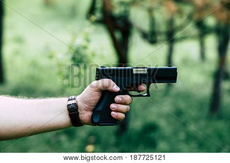 The gun is in his hand. The man is ready to shoot at the target