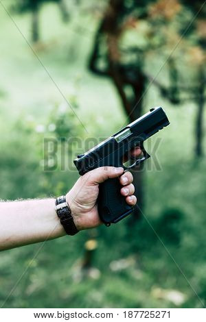 The gun is in his hand. The man is ready to shoot at the target