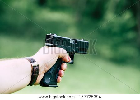 The gun is in his hand. The man is ready to shoot at the target