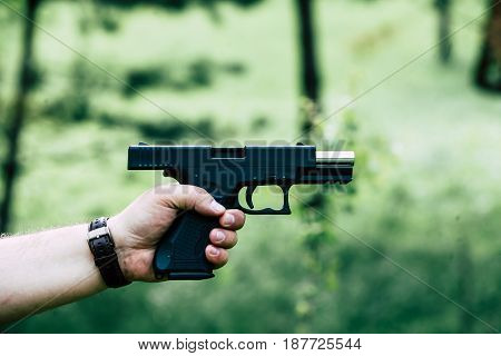 The gun is in his hand. The man is ready to shoot at the target