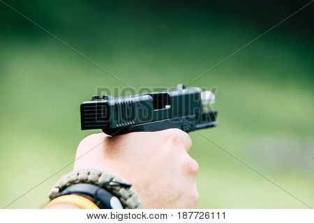 The gun is in his hand. The man is ready to shoot at the target