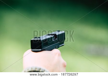 The gun is in his hand. The man is ready to shoot at the target