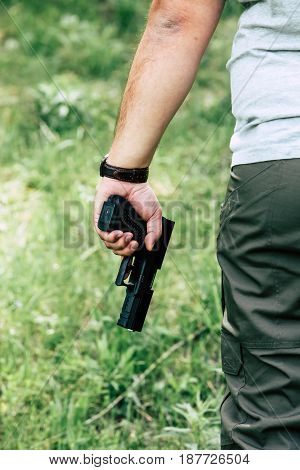 The gun is in his hand. The man is ready to shoot at the target