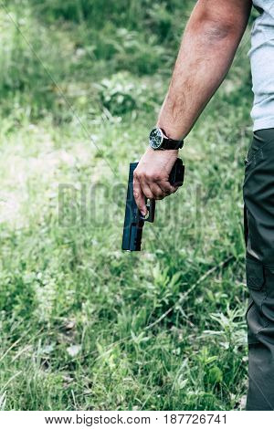 A man holds a bullet for a rifle and a pistol in his hand