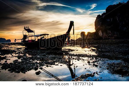 traditional long tail boat silhouette at low tide in sunset liights on Ton Sai beach, Thailand