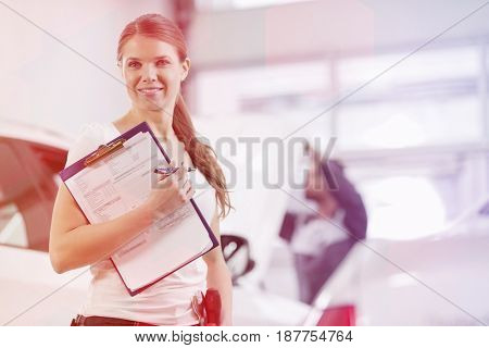 Portrait of smiling female repair worker with clipboard in car workshop