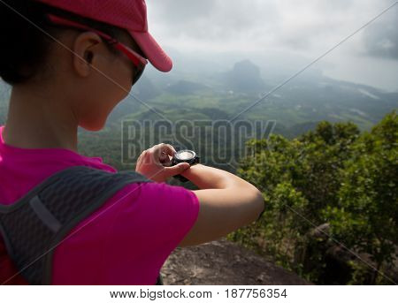 young womanhiker checking the altimeter on seaside mountain peak