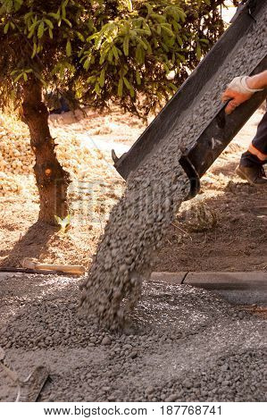 Workers work on concreting parking spaces in front of the house. Mason worker leveling concrete with trowels mason hands spreading poured concrete.