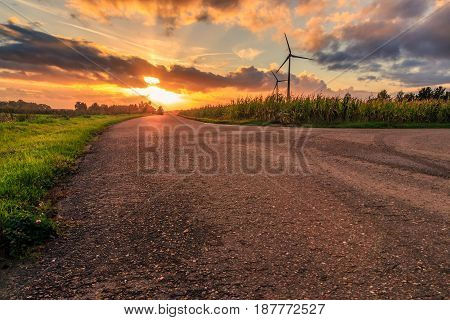 Rural scene cloudy sunset with an empty road corn fields and wind turbines. Diest Flanders Belgium Europe