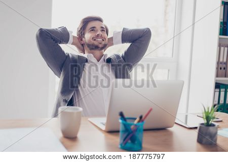 Success! Dreaming Young Bearded Entrepreneur Is Resting In Front Of Laptop At His Work Station. He I