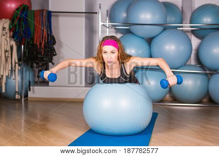 Woman exercising with dumbbells on a fitness ball.
