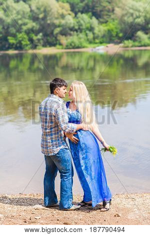 Young happy couple having fun beside river in summer sunny day