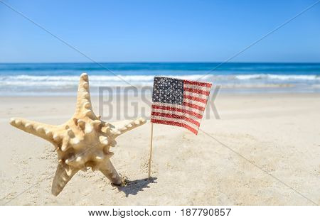 Patriotic USA background with starfish and American flag on the sandy beach