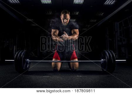 Ahlete Kneels In The Gym And Claps His Hands After Which The Dust From The Chalk Flies