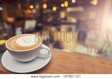 Cup of cappuccino on the table, coffee shop background, warm tone.