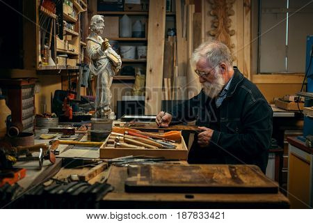 Senior wood carving professional during work