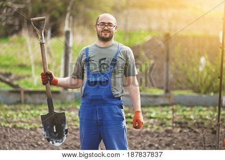 Portrait of a smiling man gardening in his garden on a lovely spring day color toned image . The gardener digs the garden with a shovel