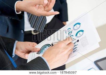Businessmen discussing and analyzing financial graph data paper
