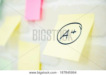 A plus grade written on notepad paper at the wall