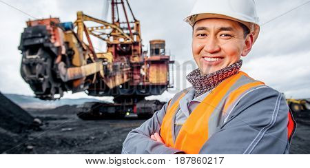 coal mining worker with rotary excavator on the background