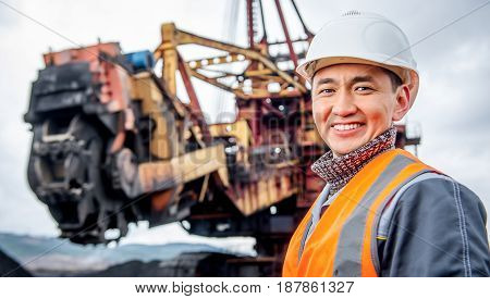 coal mining worker with rotary excavator on the background
