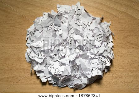 A bunch of scraps of white paper with text on a brown table