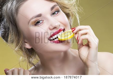 Sexy Fruit Series. Closeup Portrait of Cute Funny Naked Caucasian Girl Holding Lemon Slice In Front of Her Mouth. Posing Against Yellow. Horizontal Image Composition