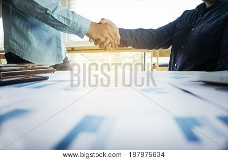 business team concept two business people shaking hands while sitting at the working place.