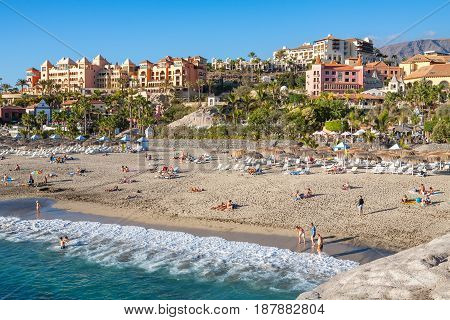 COSTA ADEJE TENERIFE SPAIN - JANUARY 31 2012: Many people sunbathing on Playa del Duque beach. Canary Islands