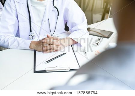 Healthcare and Medical concept patient listening intently to a female doctor explaining patient symptoms or asking a question as they discuss paperwork together in a consultation.