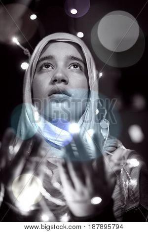 Muslim woman praying in dark room with nice lights around her