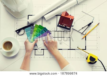 business, architecture, building, construction and people concept - close up of designer hands with color palette and house blueprint