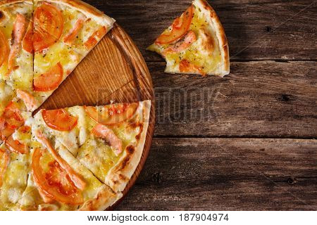 Fresh italian pizza with cut in slices served on rustic wooden table, flat lay. Calories, junk food, bad habits. Dark wooden background with free space for text.