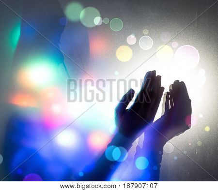Hands praying in dark room with nice lights around her