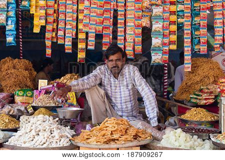 PUSHKAR INDIA - OCTOBER 28 2014: Unidentified Indian man sells sweets in the trade shop during the annual Pushkar Camel Mela. This fair is the largest camel trading fair in the world