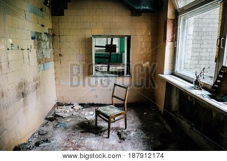 Room inside an old abandoned building, chair in the middle of the ruined room