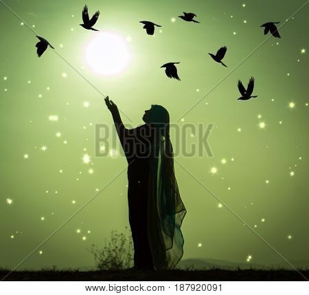 Silhouette Muslim Arabic woman praying with her hands up