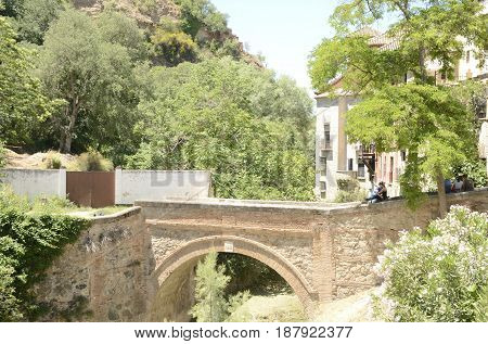 GRANADA, SPAIN - MAY 20, 2017: People on brick bridge over the river Darro in Granada Andalusia Spain.