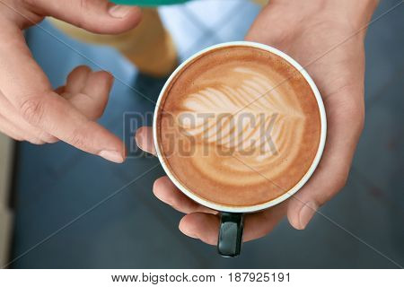 Man holding cup of coffee with latte art