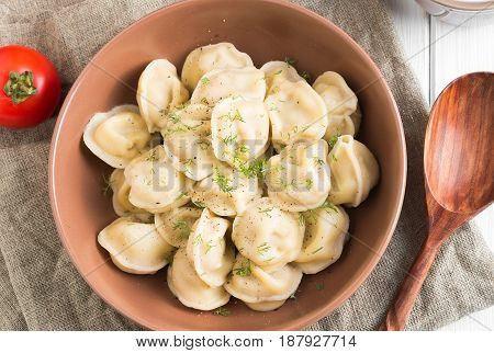 Meat dumplings tomatoes and sour cream on white wooden background. Top view