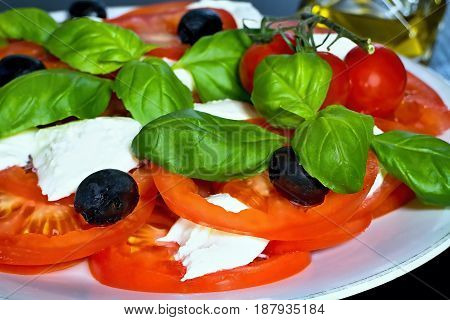 Caprese salad. Classic caprese salad. Italian traditional caprese salad ingredients. Mediterranean food. Caprese salad Tomato and mozzarella with basil leaves on wooden background.